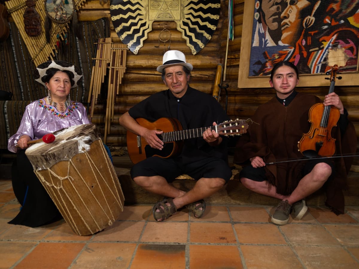 Traditional Music Three musicians with traditional instruments, dressed in the typical Saraguro dress, sitting on the floor.